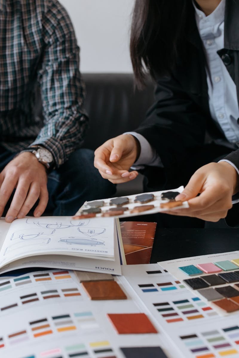 Two individuals discussing design samples and color swatches at a table, focusing on collaboration.