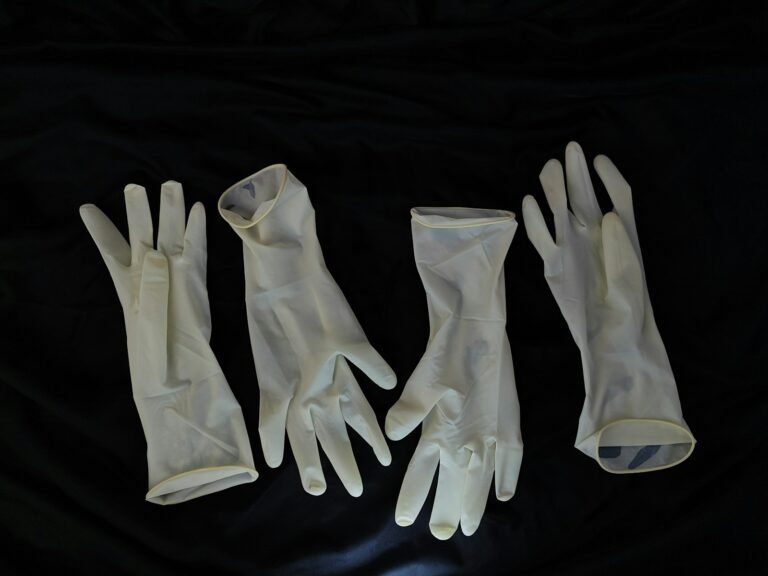 Four surgical gloves are displayed on a dark surface.