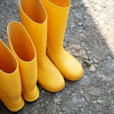 Vibrant yellow rain boots on a rocky ground, showcasing waterproof footwear design.