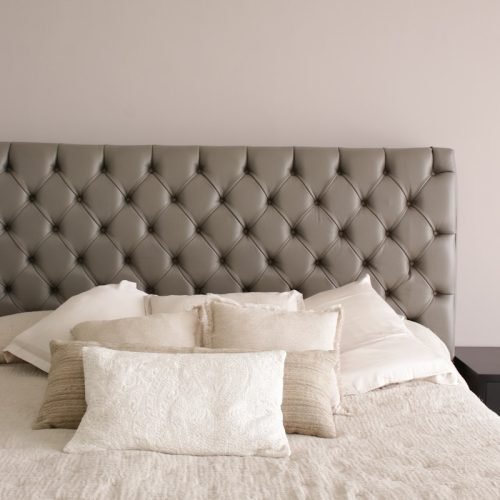a bed with a white comforter and pillows